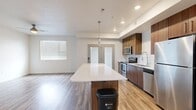 This well-designed single-floor residence offers two bedrooms and two bathrooms within a thoughtfully arranged floor plan. The open-concept kitchen and living area serves as the heart of the home, featuring a large central island with a white quartz countertop and warm wood-toned base, complemented by matching upper and lower cabinetry. A white subway tile backsplash, stainless steel appliances—including a range, microwave, refrigerator, and dishwasher—and a modern pendant light above the island complete the kitchen's contemporary aesthetic. Wood-look plank flooring runs throughout the main living and kitchen areas, adding warmth and continuity.

Both bedrooms are finished with neutral carpet and crisp white walls, providing a calm and versatile environment. The primary bedroom includes access to a dedicated walk-in closet equipped with multiple hanging rods and shelving. Both bathrooms mirror each other in design, each featuring wood-toned vanity cabinetry, white quartz countertops, undermount sinks, large frameless mirrors, and stylish multi-globe light fixtures. Wood-look flooring continues into the bathrooms, maintaining a cohesive design language. A dedicated entrance, hallway, and additional closet space round out this efficiently planned residence.