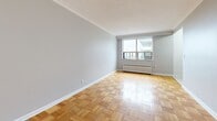Located on the 7th floor at 130 Jameson Ave in Toronto's Parkdale neighbourhood, this one-bedroom, one-bathroom unit offers a functional and well-appointed layout across a single floor. The main living area is notably spacious for a one-bedroom unit, featuring classic parquet wood flooring in a basket-weave pattern that adds warmth and character throughout. Soft grey walls and crisp white crown moulding provide a clean, neutral backdrop, while a large window floods the room with natural light and offers outward views. A traditional cast-iron radiator sits beneath the window, providing efficient heating. The compact kitchen is efficiently designed with white shaker-style cabinetry, grey countertops, light tile flooring, and stainless steel appliances including a full-size refrigerator and stove. The hallway connects the living space to the bedroom and bathroom, maintaining a logical and comfortable flow. The bathroom features full white subway tile surrounding a bathtub and shower combination, a pedestal-style vanity with a mirrored medicine cabinet, and chrome fixtures. The entry area continues the parquet flooring and leads seamlessly into the main living space, completing a cohesive and practical unit.