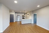 Located at 2000 Swenson Ln in Saint Peters, Missouri, this well-appointed 2-bedroom, 2-bathroom residence offers a thoughtfully designed single-level layout. The open-concept kitchen and living area serves as the heart of the home, anchored by a central island with a white countertop and sink, pendant lighting overhead, and a full suite of stainless steel appliances including a refrigerator, electric range, and over-the-range microwave. White shaker cabinetry with a light tile backsplash lines the kitchen walls, complementing the warm luxury vinyl plank flooring found throughout the unit. The spacious living area flows seamlessly from the kitchen, offering room for a variety of furniture arrangements. Both bedrooms are generously sized, featuring ceiling fans, large windows that bring in ample natural light, and outdoor views of the surrounding community. The primary bedroom offers a comfortable footprint with direct access to a private balcony via sliding glass doors. Each bathroom is finished with grey shaker vanity cabinetry, white countertops, and backlit mirrors, contributing to the clean, contemporary aesthetic. Two dedicated closets provide practical storage. The overall ambiance is bright, modern, and move-in ready, with a neutral color palette and consistent finishes throughout.