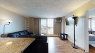 Situated on North Lake Street in the heart of Madison, Wisconsin, this single-floor unit offers a thoughtfully designed layout with warm hardwood flooring throughout. The open living area is a standout feature, anchored by a large sliding glass door that leads to a private balcony overlooking the city skyline, flooding the space with natural light. Built-in shelving adds functional character to the living room, which comfortably accommodates a full seating arrangement.

The kitchen is well-equipped with rich dark wood cabinetry, granite countertops, and stainless steel appliances including a gas range, microwave, dishwasher, and refrigerator — ideal for everyday cooking and entertaining.

The unit includes two bedrooms, each featuring hardwood floors, a window with exterior views, individual wall-mounted AC units, and ample storage with dressers and open closet shelving. Each room provides a quiet, functional space suitable for rest or work.

Two full bathrooms serve the unit, both finished with warm tile flooring, tile-surround bathtub/shower combos, and solid wood doors. The consistent use of neutral tones and natural materials throughout creates a cohesive and comfortable atmosphere well-suited to urban living in Madison.