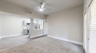 This 2-bedroom, 2-bathroom residence features a clean, modern design defined by a neutral color palette, updated finishes, and thoughtful use of space throughout. The open-concept living area is anchored by soft carpeting and a ceiling fan, flowing directly into the kitchen via a half-wall breakfast bar. The kitchen is well-appointed with gray shaker-style cabinetry, stainless steel appliances including a range, microwave, and refrigerator, white quartz countertops, and a marble-style tile backsplash, all set over light wood-look flooring. The primary bedroom offers comfortable carpeting, a ceiling fan, and French doors that invite natural light. The second bedroom is equally well-lit, featuring dual windows with blinds and its own ceiling fan. Both bathrooms echo the home's cohesive design, showcasing gray vanity cabinetry, white quartz counters, and wood-look tile flooring. The primary bath includes a tub and shower combination with elegant marble-style surround tile and brushed gold fixtures, while the second bathroom offers a streamlined vanity with modern lighting. Throughout, the space maintains a bright, clean ambiance with consistent warm-gray tones and contemporary detailing.