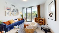Located at 6445 NE 7th Avenue in Miami's dynamic Little Haiti neighborhood, this well-appointed 2-bedroom, 2-bathroom residence offers a thoughtfully designed open-concept floor plan. The combined kitchen, dining, and living area forms the heart of the home, bathed in natural light streaming through expansive floor-to-ceiling sliding glass doors that open to a private balcony overlooking a canopy of lush greenery.

The modern kitchen is outfitted with stainless steel appliances, wood-toned cabinetry extending to the ceiling, white quartz countertops, and a decorative tile backsplash — offering both style and functionality. Light wood-look flooring runs throughout the main living areas, enhancing the bright, airy feel.

The living area is anchored by large glass sliding doors that frame picturesque outdoor views and provide seamless indoor-outdoor flow. Both bedrooms are comfortably sized, each with windows overlooking the treetops, and light wood flooring. The primary bedroom features a bold accent wall, adding a striking design element.

The bathrooms are clean and contemporary, featuring wood-toned vanities, white quartz countertops, and a tub-shower combination with crisp white tile surround. A hallway and closet complete the efficient layout of this well-designed Miami residence.
