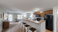 Located at 437 Sunburst Dr in Delaware, Ohio, this single-floor, 2-bedroom, 2-bathroom home offers a practical and comfortable layout. The open-concept kitchen and living room serve as the heart of the home, where a peninsula with a granite-style countertop and bar seating connects the kitchen to the main living area. The kitchen is equipped with warm wood cabinetry, black appliances including a range, microwave, and refrigerator. The adjacent living room features large windows that invite natural light and plush wall-to-wall carpeting. The primary bedroom is a generously sized retreat with dual windows, carpet flooring, and ample natural light. The second bedroom offers a similar aesthetic with carpet and multiple windows. Two full bathrooms serve the home — one features a vanity with a granite-style countertop and a stand-up glass shower, while the other includes a full tub-shower combo with tile flooring. A dedicated in-unit laundry room with a full-size washer and dryer adds everyday convenience. A hallway and closet complete the well-organized floor plan, making efficient use of the available space throughout this cozy Delaware, OH residence.