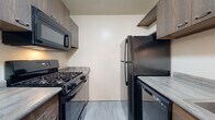 This single-floor, one-bedroom, one-bathroom unit in Allen Park, Michigan, offers a practical and well-organized layout. The entryway greets residents with plush carpeting, a large closet with paneled doors, and a stylish orb-style pendant light fixture, setting a welcoming tone throughout.

The galley-style kitchen is efficiently designed with two parallel countertops maximizing workspace. It features a complete suite of black appliances, including a gas range, over-the-range microwave, refrigerator, and dishwasher. Modern wood-toned cabinetry provides ample storage, while light-toned vinyl plank flooring adds a clean, contemporary feel.

The living area is generously proportioned, featuring soft carpeting and a full-width sliding glass door that fills the space with natural light and offers views of the surrounding greenery. A coat closet is conveniently located nearby.

The bedroom is comfortably sized with plush carpet, a window overlooking the exterior, and a floor vent for climate control.

The bathroom features light gray subway tile surrounding a full soaking tub and shower combination, complemented by light tile flooring, a window for natural light, and chrome grab bar hardware for added accessibility.