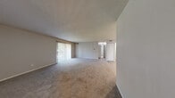 Located at 4010 North Brandywine Drive in Peoria, IL, this 2-bedroom, 2-bathroom single-floor residence offers a well-organized and functional layout. The open living room is generously sized, featuring neutral-toned carpet, a textured ceiling, and a large sliding glass door fitted with vertical blinds that floods the space with natural light and provides access to an outdoor balcony area with greenery views. The galley-style kitchen is outfitted with warm wood cabinetry, light countertops, a stainless steel sink, and light vinyl plank flooring, providing ample storage and a clean, efficient workspace with white appliances. The primary bedroom is a comfortable retreat, complete with carpeted flooring, neutral gray walls, and direct access to a private en-suite bathroom. The en-suite features a warm wood vanity with a wide countertop, a large mirror, and a tiled shower-tub combination. The second bedroom also features carpet and includes a reach-in closet with louvered doors. A second full bathroom serves the remaining rooms. Throughout the unit, consistent neutral tones, white trim, and practical finishes create a cohesive and move-in-ready ambiance.