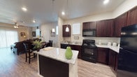 Located at 2811 Oakridge in Lubbock, this two-story home offers a well-designed layout that balances functionality and comfort across both levels. The heart of the home is an open-concept kitchen, showcasing rich espresso-toned cabinetry paired with granite countertops and a central island with pendant lighting overhead. Black appliances — including a range, microwave, dishwasher, and refrigerator — complement the kitchen's bold, cohesive aesthetic. Wood-look flooring flows throughout the main living areas, lending warmth and continuity to the space.

The living room is generous and inviting, featuring a ceiling fan, wood-look flooring, and sliding glass door access that brings in natural light. Bedrooms offer plush carpeting, ceiling fans, and windows that provide ample daylight. One bedroom includes a walk-in closet, adding notable storage convenience.

The bathrooms are thoughtfully finished with granite-topped dark wood vanities and framed mirrors that echo the design language found throughout the home. One full bathroom features a tub-shower combination, while another offers an elongated vanity with additional cabinetry for storage. The consistent use of granite surfaces, espresso cabinetry, and wood-look flooring creates a cohesive and polished interior from top to bottom.