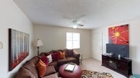 This 2-bedroom, 1-bathroom residence is thoughtfully laid out across a single floor, making it easy to navigate and efficiently use every square foot. The living area serves as the heart of the home, featuring light-toned carpet flooring, neutral-painted walls, and a ceiling fan with integrated lighting — a practical touch that supports year-round comfort. A window fitted with blinds allows natural light to filter into the space, creating a bright and welcoming atmosphere. The textured popcorn ceiling adds a classic residential character throughout. The living room offers ample space for a sectional sofa arrangement and entertainment setup, as evidenced by the well-proportioned layout. The two bedrooms provide private retreats suited for rest or work, while the single bathroom supports the home's functional design. The overall ambiance is cozy and approachable, with a straightforward floor plan that maximizes usable space. This unit is well-suited for individuals, couples, or small families seeking a manageable, single-level living arrangement with essential amenities in a compact and efficient footprint.