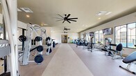 Located at 4820 SW 48th Ave in Ocala, Florida, this well-appointed fitness center offers a generously sized, single-floor layout designed to accommodate a comprehensive range of workout activities. The open floor plan provides ample space for movement between equipment zones, with neutral-toned flooring throughout that lends a clean, modern aesthetic.

The cardio section is equipped with multiple treadmills and elliptical machines, positioned along a windowed wall that allows natural light to flow in and provides views of the surrounding outdoor area, including a pool and palm trees. Wall-mounted flat-screen televisions are installed throughout for entertainment during workouts.

The strength training area features a diverse selection of resistance machines, free weights, and weight benches, offering options for both beginners and experienced athletes. Exercise balls and additional accessories are also available for functional fitness routines.

Recessed lighting and multiple large ceiling fans ensure the space remains well-lit and comfortable. A vestibule entry area with built-in shelving and seating provides an organized transition space with glass-paneled double doors leading into the main fitness floor. The light-colored walls and neutral interior palette contribute to a bright, inviting atmosphere throughout the facility.