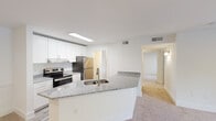Located on Wesley Place in Lawrenceville, Georgia, this single-floor residence offers a clean, well-maintained interior with a bright and neutral color palette throughout. The open-concept kitchen serves as a central highlight, featuring a large peninsula with granite countertops and an integrated sink, crisp white shaker-style cabinetry extending to the ceiling, and stainless steel appliances including an electric range and refrigerator. The kitchen flows seamlessly into the adjoining living and dining areas, which are finished with plush wall-to-wall carpeting that continues throughout the unit.

The living area is generously proportioned and benefits from a sliding glass door that opens onto a private balcony, offering pleasant views of mature greenery and landscaping. Natural light filters through the space, reinforcing the open and airy feel. The bedrooms are comfortably sized, each featuring carpet flooring, white walls, and windows fitted with horizontal blinds that allow for adjustable natural light and privacy.

The bathroom includes a full soaking tub and shower combination with white tile surround and a curved curtain rod. The overall design is cohesive and functional, with recessed lighting and central HVAC vents present throughout, contributing to a practical and comfortable living environment.