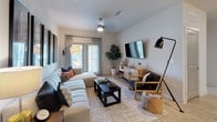 This single-floor residence blends coastal-inspired design with modern finishes throughout its thoughtfully arranged layout. The open-concept living area serves as the heart of the home, featuring light wood-style flooring, a ceiling fan, and large sliding glass doors that invite natural light and provide outdoor access. A generous sectional sofa, accent seating, and surf-themed wall art contribute to the relaxed, beachy ambiance.

The kitchen is equipped with stainless steel appliances, including a range, microwave, and dishwasher, complemented by gray shaker-style cabinetry and granite countertops. A peninsula with bar seating and pendant lighting above connects the kitchen seamlessly to the living and dining areas.

The primary bedroom features a reclaimed wood-style accent wall, plush carpeting, a ceiling fan, and ample natural light. The second bedroom carries the coastal theme with soft blue walls, hardwood-style flooring, large windows with sheer curtains, and a gallery wall of beach-inspired artwork.

Both bathrooms are finished with granite vanities, dark wood cabinetry, and shower-tub combinations. Light wood-style flooring runs consistently through the common areas, tying the entire space together with a warm, cohesive aesthetic.