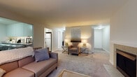 This single-floor residence offers a thoughtfully designed layout that balances comfort and functionality across its living spaces. The expansive living room serves as the heart of the home, centered around a tile-surround fireplace with a classic white mantel. Neutral carpet flooring and large windows allow natural light to fill the room, offering pleasant outdoor views of surrounding greenery. The space flows openly toward a secondary seating area, providing flexibility for various furniture arrangements.

The kitchen features wood-look vinyl flooring, crisp white cabinetry, light countertops, and stainless steel appliances including a full-size refrigerator and range. A skylight adds brightness to the efficiently organized galley-style layout. A dedicated dining area connects seamlessly to the main living spaces.

Two well-proportioned bedrooms each feature plush carpet flooring, natural window light, and sliding or hinged closet doors providing ample storage. One bedroom includes a walk-in closet with built-in shelving and a hanging rod for organized storage.

The bathroom is finished with clean, neutral tones, offering a full soaking tub and shower combination, overhead cabinetry for additional storage, and wood-look flooring. Throughout the residence, a consistent warm, neutral palette creates a cohesive and inviting ambiance.