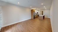 Located at 700–724 10th Ave in Belmar, NJ, this well-appointed two-bedroom, two-bathroom residence with a den offers a thoughtfully designed single-floor layout with modern finishes throughout. The open-concept living and kitchen area serves as the heart of the home, featuring warm hardwood-style flooring, recessed lighting, and a spacious central island with a crisp white quartz countertop. The kitchen is outfitted with a dual-tone cabinetry scheme — glossy white upper cabinets paired with natural wood-toned lower cabinets — along with stainless steel appliances including a gas range, built-in microwave, and refrigerator, plus a subway tile backsplash and undermount sink. The living area is generously proportioned, with access to natural light through a window with exterior views. Both bedrooms feature hardwood-style flooring and neutral gray walls, creating a calm and versatile backdrop. The primary bathroom includes a sleek walk-in shower with floor-to-ceiling white tile and a sliding glass door, while the secondary bathroom offers a tub-shower combination. Both bathrooms feature wood-toned vanities with white countertops and large-format tile flooring. A flexible den space adds additional functionality to this well-rounded residence.