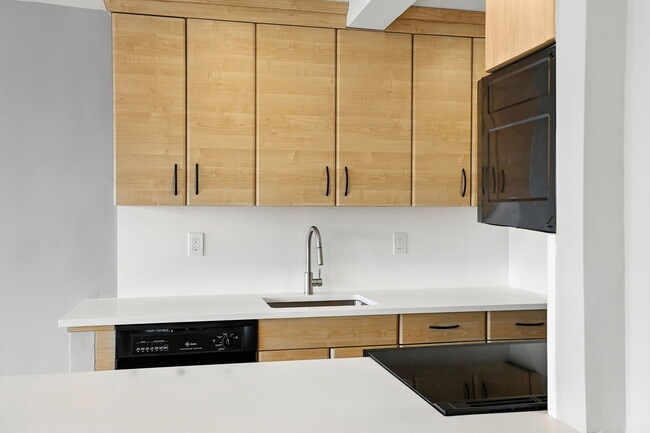 Kitchen w/ light brown, modern cabinets, black appliances, and new quartz countertops - 12 Old Mamaroneck Rd