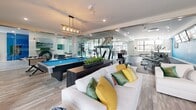 Located at 11 Stickney Avenue in Concord, New Hampshire, this amenity floor at The Lots at 93 North offers a thoughtfully designed communal space that blends modern aesthetics with practical functionality. The entry lobby sets an immediate tone with its dramatic marble-look porcelain tile flooring, a bold circular pendant light fixture, and large windows that invite natural light — all anchored by a branded welcome mat that nods to the building's Interstate 93 identity.

At the heart of the floor, a striking open-tread staircase with warm wood steps, black steel framing, and cable railings serves as both a functional and architectural centerpiece, rising against a vibrant green accent wall adorned with eclectic road signs and New Hampshire highway memorabilia. Floor-to-ceiling glass partitions divide the space into distinct zones while maintaining a sense of openness and visual connectivity throughout.

The fitness center is generously sized and well-equipped, featuring treadmills, stationary bikes, rowing machines, weight benches, and strength equipment, all set on durable rubber flooring with large windows providing ample daylight. Adjacent to the gym, a bright reception or leasing area features a bold blue accent wall, pendant lighting, and a sleek counter workspace. The lounge area offers comfortable seating, a pool table, and stylish décor, creating an inviting space for recreation and social gathering.