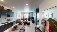 This single-floor residence is designed with a contemporary aesthetic that balances bold color choices with clean, functional design. The open-concept living and dining area serves as the heart of the unit, where light wood-look flooring flows seamlessly throughout. A striking teal accent wall anchors the living space, complementing neutral white walls and providing a vivid backdrop for the entertainment area. Natural light enters through multiple windows dressed with blinds and curtain panels, brightening the space throughout the day.

The kitchen runs along one wall and features dark cabinetry with sleek hardware, stainless steel appliances including a refrigerator, range, microwave, and dishwasher, and light countertops. A compact dining table with bar-style seating sits adjacent, creating an efficient and connected eat-in area.

The bedroom offers plush carpeting, a generously sized window, and access to a walk-in closet. A dedicated built-in workspace with floating shelves and a desk provides a practical nook for productivity. The bathroom includes dark vanity cabinetry, a round mirror, and a combined tub and shower. Recessed lighting and a cohesive color palette tie the entire unit together with a polished, modern feel.