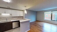 Situated in the heart of Grand Rapids, Michigan, this single-floor residence at 55 Campau Ave NW offers a well-designed layout with modern finishes throughout. The open-concept living and dining area is anchored by warm hardwood flooring and neutral gray walls, creating a bright and inviting atmosphere. Large windows allow natural light to pour in while offering views of the surrounding urban cityscape.

The kitchen is a standout feature, equipped with stainless steel appliances including a side-by-side refrigerator, electric range, and over-the-range microwave. White shaker-style cabinetry with ample storage is complemented by a subway tile backsplash and light stone countertops. A peninsula with pendant lighting provides additional prep space and a casual dining option, seamlessly connecting the kitchen to the living area.

The bedrooms are carpeted for comfort, each featuring neutral tones and generous closet space with built-in shelving. One bedroom enjoys a large window with views of the Grand Rapids skyline. The bathroom includes a tiled tub-shower combination, stone-top vanity, and clean, classic finishes. Throughout the space, consistent use of soft gray tones and modern fixtures creates a cohesive, contemporary aesthetic well-suited for urban living.