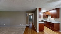 Located at 13212 Magnolia Street in Garden Grove, CA, this single-floor, 2-bedroom, 2-bathroom home offers a functional and well-organized layout. The open-concept living and dining area features warm neutral-toned walls, plush carpet flooring, and a large window dressed with blinds that allows natural light to fill the space. A wall-mounted air conditioning unit provides dedicated climate control in the living area.

The galley-style kitchen is efficiently designed with rich cherry wood cabinetry, granite-look countertops, a gas range, and a double sink. Light wood flooring runs throughout the kitchen, adding warmth and contrast to the cabinetry. The kitchen flows seamlessly into the dining and living areas via an open pass-through layout.

Both bedrooms are carpeted and feature neutral walls with textured ceilings. The primary bedroom is generously sized and includes a sliding mirrored closet, an additional standard closet, and a window with outdoor views. The second bedroom also features a window with natural light and ample open floor space. A hallway connects the private areas of the home, leading to two full bathrooms, each with a shower-tub combo. Three closets throughout the home ensure practical storage solutions.