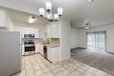 Located at 2851 S Lovers Ln in Visalia, California, this single-story residence offers a well-organized, functional layout designed for comfortable everyday living. The kitchen serves as a central highlight, featuring white raised-panel cabinetry, light stone-toned countertops, a tile backsplash, and a full suite of stainless steel appliances including a gas range, over-the-range microwave, dishwasher, and refrigerator. Light ceramic tile flooring runs throughout the kitchen and dining area, while a chandelier overhead adds a touch of elegance to the space. The open layout allows the kitchen to flow naturally into the dining and living areas, where a ceiling fan with light fixture provides comfort and circulation. Vertical blinds on the sliding glass door allow for natural light while maintaining privacy. The carpeted living and bedroom areas offer a warm, quiet atmosphere. Bedrooms are generously proportioned, each featuring ceiling fans, large sliding-door closets with rods, and windows that bring in natural light. The bathroom includes a full tub-shower combination, tile flooring, a white vanity with stone-toned countertop, and clean, neutral finishes throughout. The overall design is bright and neutral, with white walls and consistent finishes creating a cohesive, move-in-ready environment.