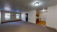 Located at 210 Washington Ave in Bridgeport, Connecticut, this single-floor unit offers a practical and well-organized layout designed for comfortable everyday living. The open-concept living area is generously proportioned, finished with wall-to-wall carpeting and neutral-toned walls that create a clean, bright atmosphere. Flush-mount ceiling lighting illuminates the space throughout, and baseboard heating runs along the exterior walls. Windows allow natural light to filter into both the living and bedroom areas, offering views of the surrounding neighborhood.

The galley-style kitchen is efficiently arranged with warm wood cabinetry lining both sides, providing ample upper and lower storage. White appliances — including a refrigerator, electric range, and dishwasher — are complemented by light countertops and a single-basin sink. The kitchen transitions smoothly into the main living area via hardwood-style flooring.

The bedrooms are carpeted and well-sized, each featuring dedicated closet space with hanging rods. The full bathroom includes a bathtub with shower, a wall-mounted sink, a toilet, a medicine cabinet mirror, and grab bars — indicating accessibility-conscious design. Wood-style flooring completes the bathroom. Overall, the unit presents a functional, no-frills layout suited for a range of residents.