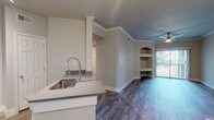 Located at 6141 Avery Dr in Fort Worth, TX, this single-story unit offers a well-designed, open layout with a cohesive blend of modern finishes and functional details throughout. The main living area features rich wood-look flooring, crown molding, and a distinctive teal accent ceiling with a ceiling fan, lending a touch of character to the space. Built-in arched shelving flanks one wall, providing both display and storage opportunities, while a sliding glass door fills the room with natural light and opens to a private patio area.

The kitchen is appointed with white cabinetry, stainless steel appliances including a range, microwave, and refrigerator, along with a peninsula that includes a deep stainless steel sink with an industrial-style faucet. Light wood-look tile flooring and track lighting complete the practical yet stylish kitchen space. A dedicated dining area nearby features warm wood-look flooring and an elegant pendant chandelier.

The bedroom offers plush carpeting, a ceiling fan, and a window overlooking lush greenery, creating a calm and comfortable retreat. The bathroom is finished with large-format textured tile surrounding a soaking tub and shower combination, complemented by wood-look flooring and brushed nickel fixtures. Overall, the space presents a clean, updated aesthetic throughout.