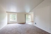 Located at 3300 Valentine Ln SE in Port Orchard, Washington, this two-bedroom, one-bathroom single-floor home offers a well-organized layout with a comfortable, functional design. The living area is a standout feature, showcasing vaulted ceilings that lend an open, airy feel to the space. Large windows and a sliding glass door flood the room with natural light while providing views of lush surrounding greenery and access to a private balcony. Plush carpeting throughout the living area and bedrooms adds warmth and comfort underfoot.

The kitchen is equipped with warm wood-toned cabinetry, granite-look countertops, a double basin sink, and white appliances including a refrigerator and range. Wood-look flooring in the kitchen and entryway provides a clean, practical surface that transitions neatly into the carpeted areas.

Both bedrooms are well-proportioned with neutral tones, carpeted floors, and ample closet space — the primary bedroom features a sliding-door closet. The bedrooms are served by a hallway connecting to the full bathroom, which includes a long vanity with a single sink, a wide mirror, and wood-look flooring. Three dedicated closets throughout the home provide generous storage. The overall ambiance is clean, bright, and move-in ready.