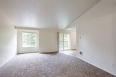 Located at 3300 Valentine Ln SE in Port Orchard, Washington, this two-bedroom, one-bathroom single-floor home offers a well-organized layout with a comfortable, functional design. The living area is a standout feature, showcasing vaulted ceilings that lend an open, airy feel to the space. Large windows and a sliding glass door flood the room with natural light while providing views of lush surrounding greenery and access to a private balcony. Plush carpeting throughout the living area and bedrooms adds warmth and comfort underfoot.

The kitchen is equipped with warm wood-toned cabinetry, granite-look countertops, a double basin sink, and white appliances including a refrigerator and range. Wood-look flooring in the kitchen and entryway provides a clean, practical surface that transitions neatly into the carpeted areas.

Both bedrooms are well-proportioned with neutral tones, carpeted floors, and ample closet space — the primary bedroom features a sliding-door closet. The bedrooms are served by a hallway connecting to the full bathroom, which includes a long vanity with a single sink, a wide mirror, and wood-look flooring. Three dedicated closets throughout the home provide generous storage. The overall ambiance is clean, bright, and move-in ready.