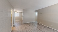 This single-floor residence offers a clean, functional layout designed for comfortable everyday living. The main living area greets you with light wood-style flooring that extends throughout the space, neutral warm-toned walls, and a textured ceiling. A large window floods the room with natural light, while a ceiling fan provides year-round comfort. The open flow connects the living area to the adjacent spaces, creating a cohesive and practical floor plan.

The galley-style kitchen is efficiently organized with white upper and lower cabinetry offering ample storage, white countertops, a stainless steel sink, and a full suite of appliances including a refrigerator, stove, and dishwasher. Matching light wood-style flooring continues seamlessly from the living areas.

The bedroom is a standout space, highlighted by a full exposed brick accent wall painted in crisp white, adding character and texture. A ceiling fan with lighting, a window with blinds for natural light and privacy, and a closet complete the room.

The bathroom is straightforward and functional, featuring a tiled shower-tub combo, a vanity with sink, and consistent flooring throughout. HVAC vents are present in key areas, ensuring climate control across the entire residence.