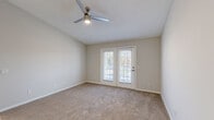 Located at 305 Brookfield Dr in Myrtle Beach, SC, this single-story, 4-bedroom, 2-bathroom home offers a practical and well-organized layout. The open-concept living room and kitchen area form the heart of the home, with the living room featuring vaulted ceilings, a ceiling fan, and plank flooring that flows seamlessly into the kitchen. The kitchen is thoughtfully appointed with white shaker-style cabinetry, white quartz countertops, a subway tile backsplash, stainless steel appliances including a range and microwave, and light hardwood-style flooring — creating a clean, modern aesthetic. The primary bedroom stands out with vaulted ceilings, a ceiling fan, plush carpeting, and glass French doors that provide access to the outdoors and fill the room with natural light. The additional bedrooms are carpeted and feature neutral tones, windows with blinds, and ample space. Both bathrooms are equipped with full tub-and-shower combinations. The home also includes three closets, a utility room, and a connecting hallway, ensuring efficient use of space throughout. The overall interior palette of soft grays and whites gives the home a bright, neutral, and move-in-ready feel.