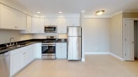 Located at 25C Shore Drive in Peabody, Massachusetts, this single-floor residence offers a thoughtfully designed layout with a clean, modern aesthetic throughout. The open-concept living and dining area is anchored by warm hardwood flooring and crown molding, with sliding glass doors leading to an outdoor balcony that fills the space with natural light. The kitchen is well-equipped with white shaker-style cabinetry, dark granite countertops, stainless steel appliances including a gas range, microwave, dishwasher, and refrigerator, and tile flooring that transitions seamlessly into the living area.

The bedrooms feature neutral-toned carpet and individual windows that provide natural light and outdoor views. One bedroom includes a spacious walk-in closet outfitted with wire shelving and hanging rods, offering generous storage capacity. The unit includes two bathrooms, both finished with white cabinetry, dark granite vanity tops, tile flooring, and mirrored medicine cabinets. One bathroom features a walk-in shower stall, while the second serves as a full bath. Neutral warm-beige walls and white trim are consistent throughout, creating a cohesive and inviting atmosphere.