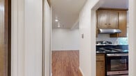 Located in Oakland, CA (94610), this efficiently designed single-floor unit makes excellent use of its intimate footprint. Rich, warm hardwood-style flooring flows consistently throughout the main living areas, anchoring the space with a cohesive and inviting aesthetic. Recessed lighting illuminates the open living area, which features clean white walls, crisp white baseboards, and a sliding glass door that welcomes natural light and provides views of the outdoors. A hallway connects the rooms seamlessly, lined with mirrored sliding closet doors that reflect light and enhance the sense of space. The kitchen is well-appointed with warm wood cabinetry featuring glass-front upper doors, dark granite-style countertops, a stainless steel sink, a stainless steel dishwasher, and a gas range — complemented by a sliding door that brings in additional natural light. The bathroom offers a clean, bright aesthetic with marble-style tile flooring, a wide vanity with white cabinetry, a large mirror, and generous built-in storage above. Overall, the unit presents a practical and polished living environment with thoughtful finishes throughout.
