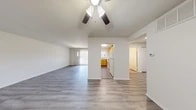 This single-story home offers a well-organized layout designed to accommodate large households with ease. The open living area greets you upon entry, featuring smooth hardwood-style flooring and a ceiling fan with light fixture overhead. Vaulted ceilings lend an airy, open feel to the main living space, which flows naturally toward the kitchen and hallway beyond.

The kitchen is equipped with warm honey-toned wood cabinetry, white countertops, a double-basin sink, a dishwasher, and a range — all complemented by a window that brings in natural light and views of outdoor greenery. The space is both functional and efficiently arranged.

Five bedrooms provide versatile options for residents, with the generously sized primary bedroom featuring durable luxury vinyl plank flooring, offering a clean and modern aesthetic. The remaining bedrooms are carpeted and bright, with multiple windows inviting natural light throughout. Closet space is well-represented, including a walk-in closet with built-in shelving.

The two bathrooms are finished in neutral tones with tile-surround tub/shower combinations and wood-style flooring. Two dedicated laundry areas — each with a full-size washer and dryer — add a notable level of convenience. The home's clean, neutral palette throughout creates a welcoming and move-in-ready environment.
