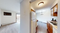 This single-floor, 1-bedroom, 1-bathroom unit offers a functional and efficient layout across a compact but thoughtfully organized floor plan. The living area is carpeted and bathed in natural light from a large sliding glass door that opens to a private balcony, offering pleasant outdoor views. Baseboard heating runs along the perimeter walls, ensuring consistent warmth throughout. A wall-mounted HVAC unit provides additional climate control in the living space.

The galley-style kitchen is equipped with warm oak cabinetry on both sides, offering ample upper and lower storage. White appliances include a coil-burner electric range and a full-size refrigerator. The kitchen features hardwood-style flooring, a stainless steel sink with a window-adjacent counter, and a textured ceiling with flush-mount lighting and a small chandelier in the adjacent dining area.

The bedroom is a comfortable size, featuring plush carpet, a sliding double-door closet with rich wood-toned panels, and a window that allows natural light and outdoor views. The full bathroom includes tile flooring, a tub/shower combination with white subway tile surround, a vanity with storage, and cool-toned walls that create a clean, calm aesthetic.

A connecting hallway ties all rooms together efficiently, completing this practical and well-maintained residential unit.