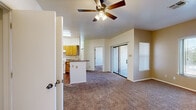 This single-floor, 2-bedroom, 1-bathroom unit offers a well-organized layout designed for comfortable everyday living. The open living area features plush wall-to-wall carpeting, a ceiling fan with integrated lighting, and a sliding glass door that connects to an outdoor patio, allowing natural light to flow into the space. A dedicated window provides additional ventilation and views of surrounding greenery.

The kitchen is efficiently designed with warm honey-toned wooden cabinetry, laminate countertops, a peninsula-style breakfast bar, and white appliances including a refrigerator and electric range. An adjacent closet offers extra pantry or storage space, enhancing the kitchen's overall functionality.

Both bedrooms are carpeted and equipped with ceiling fans. The primary bedroom is a comfortable size and features two windows that bring in natural light and views of nearby trees. The second bedroom similarly benefits from a window with outdoor views, making both rooms bright and airy.

The bathroom includes a full tub-shower combination finished with white subway tiles accented by a blue tile border, and is fitted with stainless steel grab bars. The unit also includes two closets, providing ample storage throughout the home.