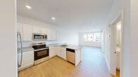 Located at 200 Garden St in South Burlington, Vermont, this one-bedroom, one-bathroom unit offers a clean, modern design throughout its single-floor layout. Light wood-tone flooring runs continuously through the space, complementing the bright white walls and creating a cohesive, contemporary feel.

The open-concept kitchen and living area forms the heart of the unit. The kitchen is well-appointed with white shaker-style cabinetry, light stone-look countertops, a stainless steel refrigerator, electric range, over-the-range microwave, and a peninsula with a sink — providing both ample prep space and a natural division between the kitchen and living area. A baseboard heating system runs along the living room wall.

The bedroom is a comfortable size, featuring large windows that flood the room with natural light and offer views of the surrounding neighborhood. A wall-mounted mini-split unit provides supplemental heating and cooling, alongside a baseboard heater.

The bathroom is finished with a white vanity, a walk-in shower stall, and wood-look flooring, maintaining the clean aesthetic found throughout the unit. A dedicated laundry room adds everyday convenience. The unit's modern finishes, abundant natural light, and functional layout make it a practical and attractive living space.