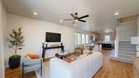 Located in Bixby, Oklahoma, this contemporary two-story home offers a thoughtfully designed layout across two floors. The main level encompasses the majority of the living space, featuring an open-concept living room, dining area, and kitchen. The living room is bright and welcoming, with warm wood-look flooring, recessed lighting, and a ceiling fan — flowing seamlessly into the dining and kitchen areas. The kitchen is well-appointed with gray shaker-style cabinetry, a decorative tile backsplash, stainless steel appliances, a butcher block island with seating, and direct access to the exterior. A dedicated office, pantry, laundry room with washer and dryer, and an attached garage add everyday convenience on the main floor. Three bedrooms — including a generously sized primary suite — are served by six bathrooms, with carpeted secondary bedrooms each featuring ceiling fans and closets. Bathrooms are finished with wood-look flooring, white cabinetry, and black hardware accents. The upper floor provides additional flexible space. Outside, the property features a covered patio, a fully fenced backyard with a gate, and a wide concrete driveway, all set against open Oklahoma skies.