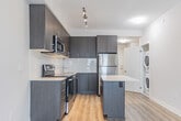 Located at 2550 Eglinton Ave W in Mississauga, this modern 1-bedroom, 2-bathroom unit offers a thoughtfully designed open-concept layout finished with contemporary details throughout. Light hardwood-style flooring flows seamlessly through the living and kitchen areas, complementing the neutral warm-toned walls that create a bright, airy atmosphere.

The kitchen is a standout feature, equipped with full stainless steel appliances including a refrigerator, electric range, over-the-range microwave, and dishwasher. Dark wood-grain cabinetry extends to the ceiling for ample storage, accented by a white subway tile backsplash and light quartz countertops. A central island provides additional prep space and casual seating. In-suite stacked laundry is also conveniently located within the unit.

The living area is bathed in natural light through large floor-to-ceiling sliding glass doors that open onto a private balcony, offering open views of the surrounding Mississauga cityscape. The bedroom also features direct balcony access via expansive windows, enhancing its bright and airy feel.

Both bathrooms are finished with clean, modern tile work. The main bathroom includes a soaker tub with a subway-tiled surround, while the second bathroom features a vanity with dark wood cabinetry and quartz countertop. A hallway connects all spaces efficiently, completing this well-appointed unit.