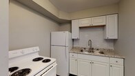 Located at 1440-1491 W Rich St in Columbus, Ohio, this single-floor unit offers a well-maintained and thoughtfully updated interior. The kitchen is equipped with white cabinetry, granite-style countertops, a subway tile backsplash, a double-basin sink with a modern faucet, a full-size refrigerator, and an electric range — providing a functional and attractive space for cooking. The living area features light-toned, hardwood-style flooring throughout, neutral gray walls, and clean white trim, creating a bright and cohesive aesthetic. A wall-mounted electrical panel is conveniently accessible from the main living space. The bedrooms continue the same flooring and neutral color palette, each offering generous closet space with built-in shelving and rods. Natural light filters in through windows fitted with blinds, offering views of the surrounding outdoor greenery. The bathroom includes a full tub and shower combination with a clean white surround featuring built-in recessed shelving niches. Ceiling fans are present in multiple rooms, adding both comfort and functionality. The overall design emphasizes simplicity and practicality, making this a clean, move-in-ready space in a residential Columbus neighborhood.