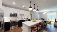 Located at 600 Willard St in Durham, NC, this single-floor residence delivers a thoughtfully designed, contemporary living experience. The open-concept kitchen is a standout feature, showcasing a striking two-tone cabinetry scheme with crisp white upper cabinets and bold dark lower cabinets, complemented by white quartz countertops, a subway tile backsplash, and stainless steel appliances. A central island with pendant lighting and bar seating flows naturally into the dining and living areas, creating an ideal layout for entertaining. Hardwood-style flooring runs throughout the main living spaces, adding warmth and continuity. The bedrooms offer comfortable retreats, with one featuring a bold navy accent wall and ample natural light from large windows. Each bedroom benefits from dedicated walk-in closet space, complete with wire shelving systems for organized storage. The bathrooms are finished with tile flooring, white vanities with quartz countertops, and a glass-enclosed walk-in shower. One bathroom provides direct access to a walk-in closet, enhancing the functionality of the primary suite. Recessed lighting throughout the home ensures a bright, well-lit environment in every room.