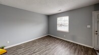 Located at 3900 Hahns Lane in Greensboro, NC, this two-story, 2-bedroom, 1-bathroom home offers a practical and well-organized layout spread across two floors. The main level features a combined dining room and kitchen, a living room, and a patio for outdoor access. The kitchen is equipped with white cabinetry offering ample storage, black appliances including a refrigerator and electric range, a double sink, and light countertops — all set on durable wood-look LVP flooring that extends throughout the main level. The living room is bright and open, with neutral gray walls and natural light from a window overlooking the exterior. A carpeted staircase leads to the upper level, where both bedrooms are located. The primary bedroom is a comfortable size and includes its own closet, while the second bedroom also features carpet flooring, gray walls, and a window allowing natural light. The full bathroom includes a tub-shower combination. The home features four closets in total, providing generous storage throughout. Textured ceilings and clean white trim are consistent throughout the space, giving it a cohesive, neutral aesthetic well-suited for easy personalization.