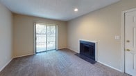 This single-floor residence offers a functional and comfortable layout with several notable features throughout. The living room serves as the centerpiece of the home, highlighted by a tile-surround fireplace and sliding glass doors with vertical blinds that open to an outdoor area, allowing natural light to fill the carpeted space. Recessed lighting adds a warm ambiance to the room.

The kitchen is designed for practicality, featuring warm wood cabinetry, granite-style countertops, a stainless steel sink, and white appliances including a range. The kitchen opens directly to the adjacent living and dining areas, creating a connected flow between spaces. Wood-style flooring runs throughout the kitchen, providing a clean contrast to the carpeted rooms.

The bedroom is a quiet, well-proportioned room with soft carpet underfoot and a window that invites natural light and outdoor views, contributing to a bright and restful atmosphere. A textured ceiling is consistent throughout the home.

The bathroom is efficiently laid out, complete with a single-sink vanity topped with granite-style counters, warm wood cabinetry, a full tub-and-shower combo with white tile surround, and wood-style flooring. Overall, the space presents a practical and inviting environment suitable for comfortable everyday living.