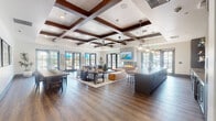 Located at 1692 Sycamore Dr in Simi Valley, California, this beautifully designed single-story clubhouse offers a refined and versatile gathering space with a cohesive modern-transitional aesthetic. The expansive main lounge is an immediate focal point, showcasing dramatic coffered ceilings with rich dark wood beams, wide-plank hardwood-style flooring, and a sleek linear fireplace. Generous windows and glass-paned French doors line the walls, flooding the space with natural light and providing views of the surrounding outdoor areas. A large, comfortable seating arrangement anchors the lounge, complemented by a wall-mounted flat-screen TV and ceiling fans overhead.

The full-service kitchen area is outfitted with a long island with bar seating, dark textured cabinetry, a shimmering tile backsplash, open shelving, beverage refrigerators, and pendant lighting that adds a warm, industrial touch. Adjacent to the main lounge is a dedicated game and entertainment zone, featuring a regulation billiards table set beneath a bold blue tray ceiling with statement pendant fixtures, an arcade game cabinet, and a comfortable lounge seating area with patterned rugs. A bright entry vestibule with hardwood flooring and large windows provides a welcoming transition into the space. Throughout, the design balances social functionality with stylish, upscale finishes.