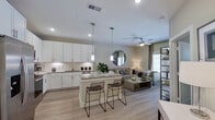 This thoughtfully designed single-floor residence offers a seamless blend of modern style and functional living. The open-concept layout connects the kitchen, dining, and living areas into one cohesive space, creating an airy, welcoming atmosphere. Light wood-tone flooring flows throughout, complemented by neutral gray and white tones that lend a clean, contemporary feel.

The kitchen is a standout feature, outfitted with crisp white shaker cabinetry extending to the ceiling, a classic subway tile backsplash, granite countertops, and a full suite of stainless steel appliances including a refrigerator, range, microwave, and dishwasher. A central island with seating for two serves as both a prep space and casual dining area, illuminated by sleek pendant lighting. The adjoining living area is anchored by a ceiling fan and benefits from natural light through well-placed windows.

The bedroom is a serene retreat, featuring a ceiling fan, natural light from curtained windows, and convenient access to an in-unit stacked washer and dryer closet. The full bathroom offers a granite-topped vanity with white cabinetry, a large mirror, and a shower-tub combination. Completing the private quarters is a generously sized walk-in closet with built-in shelving and hanging rods, providing ample organized storage.