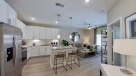 This thoughtfully designed single-floor residence offers a seamless blend of modern style and functional living. The open-concept layout connects the kitchen, dining, and living areas into one cohesive space, creating an airy, welcoming atmosphere. Light wood-tone flooring flows throughout, complemented by neutral gray and white tones that lend a clean, contemporary feel.

The kitchen is a standout feature, outfitted with crisp white shaker cabinetry extending to the ceiling, a classic subway tile backsplash, granite countertops, and a full suite of stainless steel appliances including a refrigerator, range, microwave, and dishwasher. A central island with seating for two serves as both a prep space and casual dining area, illuminated by sleek pendant lighting. The adjoining living area is anchored by a ceiling fan and benefits from natural light through well-placed windows.

The bedroom is a serene retreat, featuring a ceiling fan, natural light from curtained windows, and convenient access to an in-unit stacked washer and dryer closet. The full bathroom offers a granite-topped vanity with white cabinetry, a large mirror, and a shower-tub combination. Completing the private quarters is a generously sized walk-in closet with built-in shelving and hanging rods, providing ample organized storage.