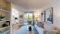 This single-floor, one-bedroom residence in Walnut Creek, California, offers a well-organized layout that maximizes its compact footprint. Wood-look flooring runs throughout, providing a cohesive and warm aesthetic, while textured ceilings add a classic architectural detail.

The living area serves as the heart of the unit, featuring a sliding glass door that opens to a private balcony overlooking lush greenery. This connection to the outdoors brings abundant natural light into the space, creating a bright and inviting atmosphere. A wall-mounted HVAC unit ensures year-round comfort.

The kitchen is efficiently designed with white cabinetry, dark granite countertops, and white appliances, including an electric range with over-the-range microwave and a full-size refrigerator. Adjacent to the kitchen, a dedicated dining nook accommodates a small table and provides a cozy space for meals, accented by neutral walls and decorative wall art.

The primary bedroom is generously proportioned relative to the overall unit size, comfortably fitting a full-size bed alongside additional furnishings. A closet with a paneled door offers practical storage. The room maintains the same warm flooring and textured ceiling found throughout, contributing to a consistent and comfortable ambiance across the entire residence.