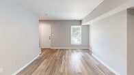 Located at 1603 Roane St in Richmond, Virginia, this two-story residence offers three bedrooms and three bathrooms across a well-organized floor plan. The main level serves as the heart of the home, featuring an open-concept kitchen and living area. The kitchen is outfitted with white shaker-style cabinetry, granite countertops, stainless steel appliances including a range, over-the-range microwave, and refrigerator, plus a peninsula with a built-in sink — ideal for both cooking and casual dining. The living room receives natural light through windows with blinds and flows seamlessly from the kitchen. Consistent light-toned hardwood-style flooring runs throughout both levels, lending a clean and cohesive aesthetic. Soft gray-toned walls complement the neutral palette across all rooms. The bedrooms are well-proportioned, with the primary bedroom featuring an open closet with shelving and direct access to its own bathroom. Secondary bedrooms include double-door closets. The bathrooms are cleanly finished, with one featuring a full tub/shower combo with built-in shelving. A staircase connects the two floors, and a hallway provides efficient circulation throughout. The upper level offers a more private retreat for the bedrooms, while the main floor handles all living and entertaining functions.