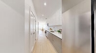 Located at 475 Main Street in Orange, NJ, this thoughtfully designed one-bedroom, one-bathroom residence offers a clean, modern aesthetic with high-quality finishes throughout. The galley-style kitchen runs along one side of the entry corridor, showcasing flat-front cabinetry in soft grey and white tones, a white quartz countertop, subway tile backsplash, stainless steel appliances including a microwave and dishwasher, and recessed lighting overhead. Light oak hardwood flooring flows seamlessly throughout the space, contributing to a bright, cohesive feel. The living room is bathed in natural light from a large window offering open views of the surrounding area, creating an airy and inviting atmosphere. The bedroom is a serene retreat with crisp white walls, light hardwood floors, and a spacious walk-in closet with built-in shelving and hanging storage. A second closet provides additional storage convenience. The bathroom features large-format floor tiles, full-height taupe wall tiles surrounding a soaking tub and shower combination, and brushed gold hardware accents. Two dedicated closets enhance the overall storage capacity of this well-appointed residence.
