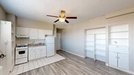 Located at 363 New St in Macon, Georgia, this efficiently designed single-floor unit offers a practical and well-organized layout. The combined living and dining area serves as the heart of the space, featuring light gray laminate hardwood flooring, neutral-toned walls, and a ceiling fan with integrated lighting that provides both airflow and illumination. A wall-mounted heating unit and a window with blinds allow for natural light and climate control. Built-in open shelving units are integrated into the living area, offering convenient storage and display options. The kitchen is finished with white cabinetry, a tile backsplash, granite-style countertops, a gas range, and a full-size refrigerator, all set atop classic white tile flooring. Open shelving within the kitchen provides additional storage. The bathroom features a clean, classic design with penny-round mosaic tile flooring, a pedestal sink, a mirrored medicine cabinet, a wall-mounted light bar, and a tiled shower-tub combination. A closet with built-in shelving and cabinetry adds further organizational functionality to the unit. Throughout the space, a consistent neutral color palette and clean finishes create a bright, cohesive atmosphere suited for practical everyday living.
