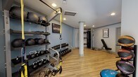 Located at 700 Garden Woods Dr in Birmingham, Alabama, this single-floor fitness facility is thoughtfully designed to support a wide range of workout routines. The space features warm-toned luxury vinyl plank flooring throughout, recessed lighting, and a clean, neutral color palette of soft gray and white tones that creates a focused, professional atmosphere.

The cardio zone is anchored by multiple treadmills and an elliptical machine, complemented by a wall of large mirrors that visually expand the space and allow users to monitor their form. A wall-mounted television is positioned nearby for added convenience. Natural light filters in through large windows at the far end, offering views of the surrounding greenery.

The strength training area is comprehensively stocked with a full rack of kettlebells and dumbbells in varying weights, medicine balls, a TRX suspension training system, a multi-function cable machine, an adjustable workout bench, a plyo box, and a recumbent bike. Structural columns are integrated naturally into the layout without interrupting the flow of the space.

Motivational framed artwork and bold signage are displayed throughout, reinforcing an energizing environment. The facility also includes an exit door with exterior access, adding practicality to the overall layout. This space offers a complete, professional-grade fitness experience.