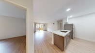 Located at 221 Smilax Rd in Vista, California, this well-appointed single-floor unit offers a clean, modern aesthetic throughout. The open-concept layout seamlessly connects the kitchen and living area, creating a bright and airy atmosphere enhanced by light wood-style flooring that runs throughout the space.

The kitchen is a standout feature, equipped with stainless steel appliances including a refrigerator, range, and microwave. Two-tone cabinetry — white upper cabinets paired with warm gray lower cabinets — is complemented by a white quartz countertop and a subway tile backsplash. A peninsula with a built-in sink adds both functionality and a natural divider between the kitchen and living area. Recessed lighting and a ceiling fan keep the space well-lit and comfortable.

The spacious living area benefits from a sliding glass door that opens to a private balcony, inviting natural light and outdoor views. Bedrooms are generously sized, each featuring light wood flooring, large windows with outdoor views, and individual wall-mounted AC units for climate control.

The bathrooms are finished with white cabinetry, quartz countertops, framed mirrors with modern fixtures, and hardwood-style flooring, delivering a crisp, updated look. Built-in shelving near one bathroom provides convenient additional storage. The overall design is clean, contemporary, and move-in ready.