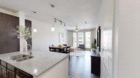 Located at 2604 Aldrich St in Austin, TX 78723, this single-story, one-bedroom, one-bathroom residence offers a thoughtfully designed layout across a compact yet efficient floor plan. The open-concept living, dining, and kitchen area forms the heart of the home, creating a seamless flow ideal for everyday living and entertaining. The kitchen is a standout feature, showcasing dark espresso cabinetry, granite-look countertops, a large peninsula with a double sink, pendant lighting, and a full suite of stainless steel appliances including a refrigerator, range, and microwave. Track lighting above the dining area further enhances the space's modern aesthetic. The living room is bright and welcoming, with natural light streaming through large windows dressed in sheer curtains, complemented by warm wood-look flooring that runs throughout the unit. The bedroom is a comfortable retreat, offering windows with views to the surrounding neighborhood, a ceiling fan, and direct access to a dedicated closet and the full bathroom. The bathroom features a glass-enclosed walk-in shower, dark wood vanity cabinetry, and warm wood-look tile flooring, providing a clean and functional finish. This residence combines modern finishes with a practical layout in a vibrant Austin location.